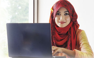 Stylish muslim woman wearing red scarf smiling while typing on h
